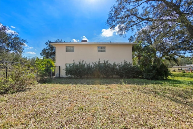 view of property exterior with fence, a lawn, and stucco siding