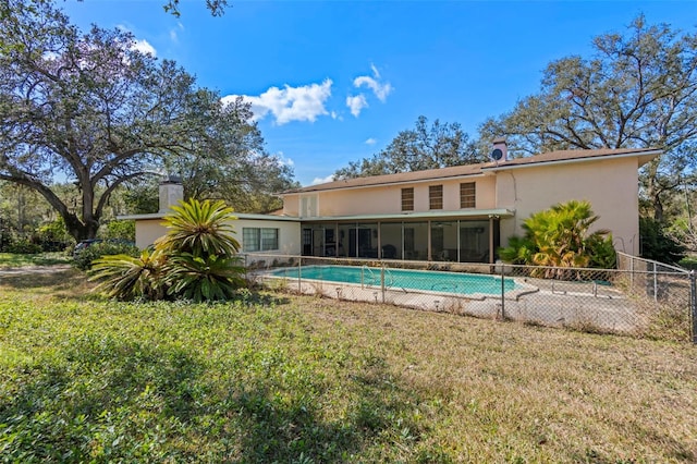 rear view of property featuring a yard, fence, a fenced in pool, and a sunroom