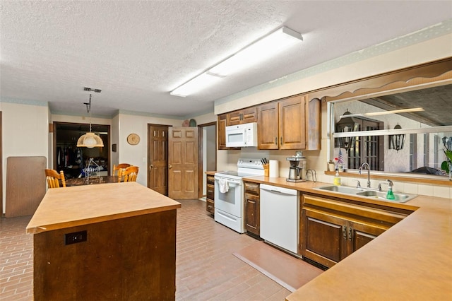 kitchen featuring visible vents, a center island, brick floor, white appliances, and a sink