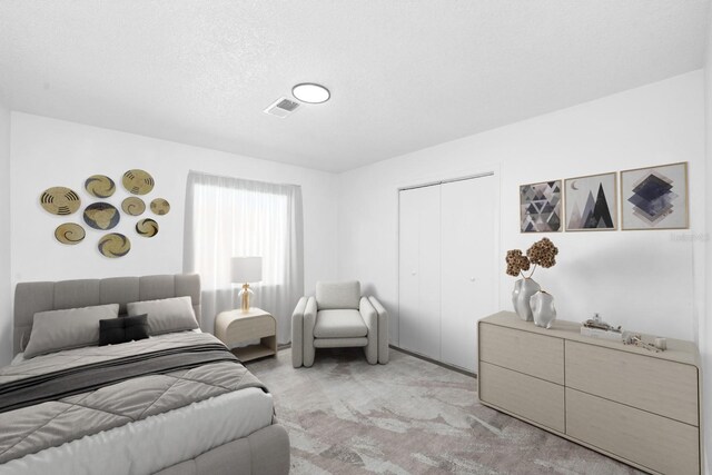 bedroom with visible vents, a closet, and light carpet