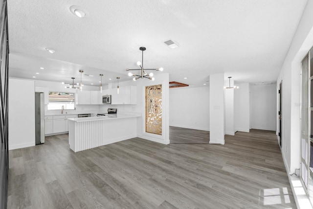 kitchen featuring open floor plan, white cabinets, appliances with stainless steel finishes, and an inviting chandelier