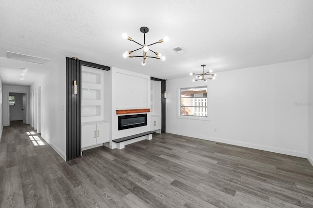 unfurnished living room featuring baseboards, visible vents, dark wood-type flooring, a textured ceiling, and a notable chandelier