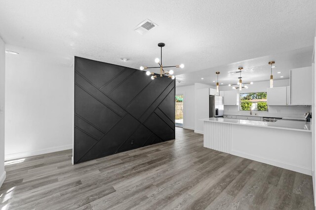 kitchen featuring visible vents, stainless steel fridge, white cabinets, light wood-type flooring, and a chandelier