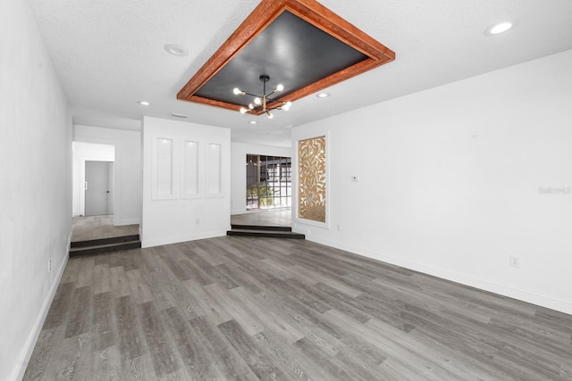 interior space with recessed lighting, baseboards, a raised ceiling, and wood finished floors