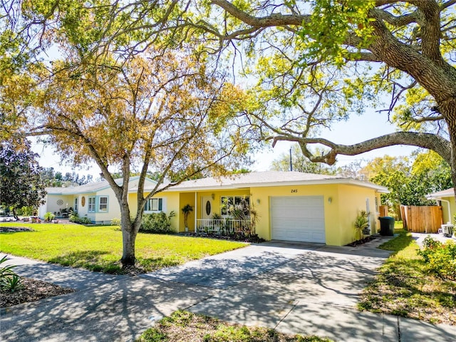 single story home featuring fence, an attached garage, stucco siding, a front lawn, and concrete driveway