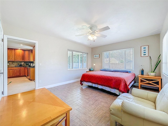 bedroom featuring baseboards, ensuite bath, and ceiling fan