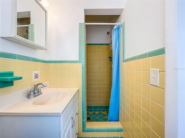 bathroom featuring vanity, a shower stall, tile walls, and a wainscoted wall