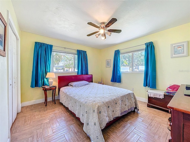 bedroom with baseboards, multiple windows, and a ceiling fan