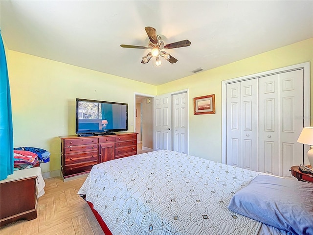 bedroom featuring visible vents, two closets, and ceiling fan