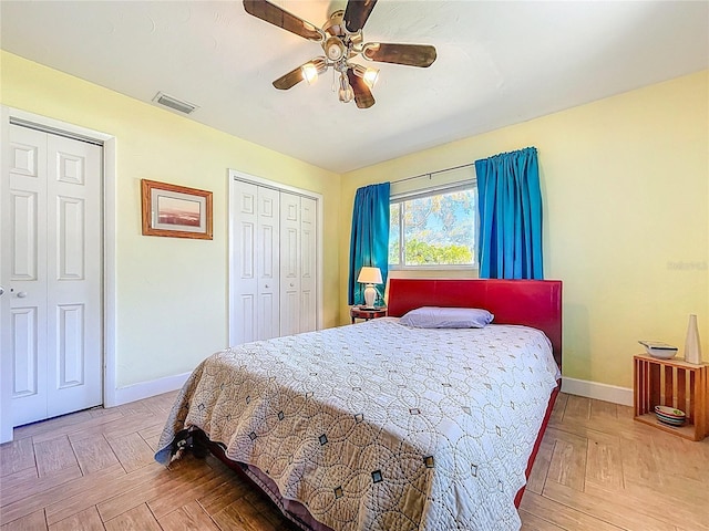 bedroom with visible vents, baseboards, two closets, and a ceiling fan