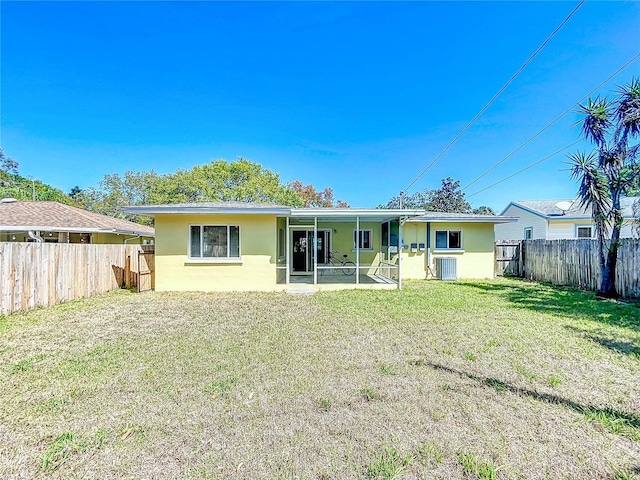 rear view of property featuring stucco siding, a lawn, a fenced backyard, cooling unit, and a sunroom