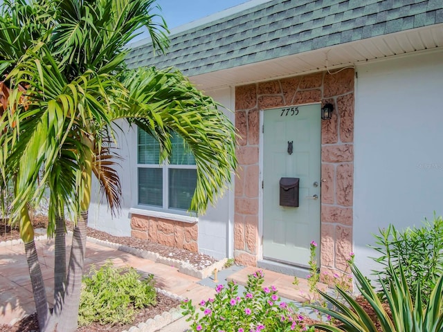 property entrance featuring mansard roof and roof with shingles