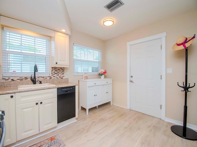 kitchen featuring white cabinets, dishwasher, light countertops, and a sink