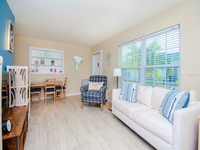 living room with built in features, light wood-type flooring, and baseboards