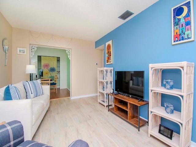 living room with wood finished floors, visible vents, and baseboards