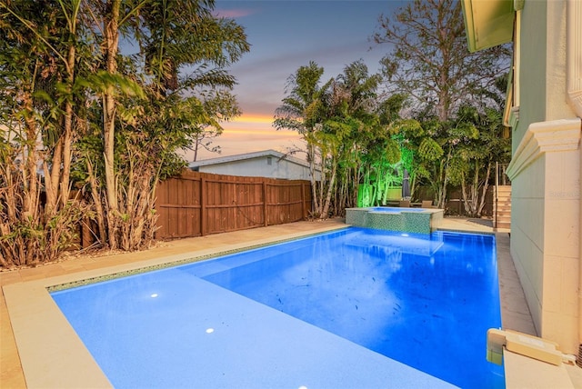 view of swimming pool featuring a pool with connected hot tub and a fenced backyard