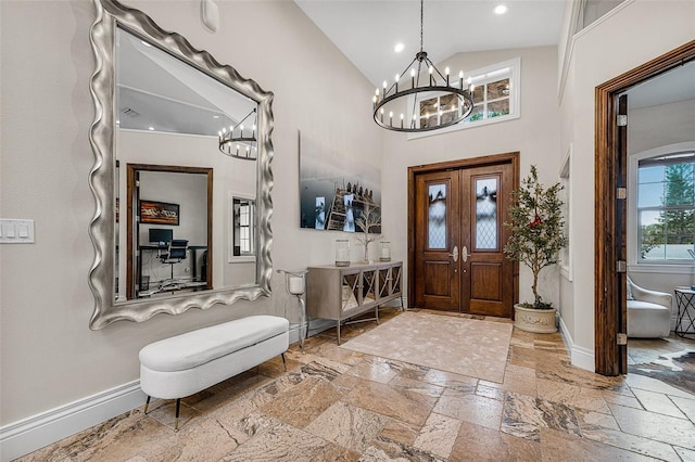 entryway with baseboards, recessed lighting, an inviting chandelier, stone tile flooring, and high vaulted ceiling