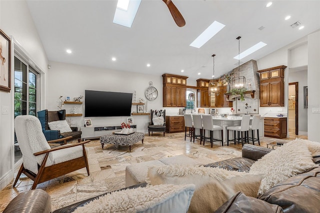 living area with visible vents, stone tile floors, recessed lighting, a skylight, and high vaulted ceiling