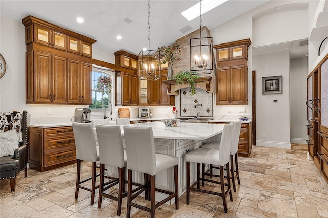 kitchen with brown cabinets, stone tile floors, a center island, a breakfast bar area, and baseboards