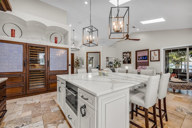 kitchen with oven, high vaulted ceiling, stone tile flooring, white cabinets, and light stone countertops