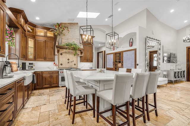 kitchen featuring a notable chandelier, high end stove, stone tile floors, and range hood