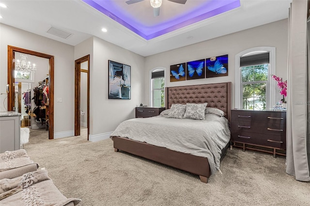 carpeted bedroom with a ceiling fan, baseboards, a spacious closet, a closet, and a raised ceiling