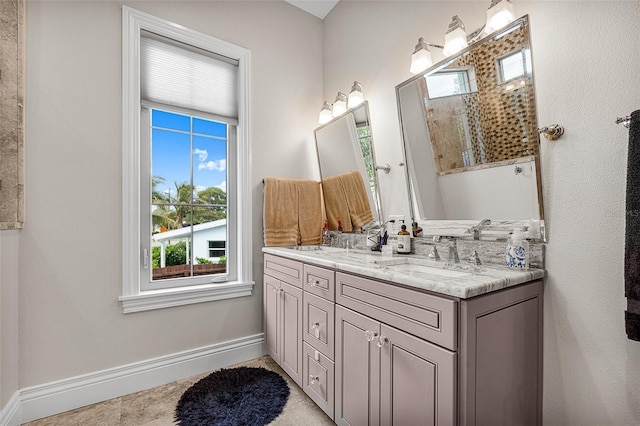 full bathroom with walk in shower, baseboards, double vanity, tile patterned floors, and a sink