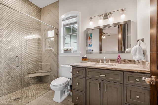 full bath with a stall shower, toilet, vanity, and ceiling fan