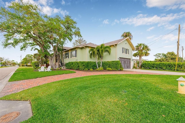 view of front of house featuring stucco siding, a front yard, decorative driveway, and a garage