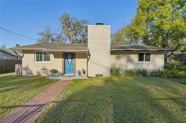 view of front of home with stucco siding, a chimney, a front yard, and fence