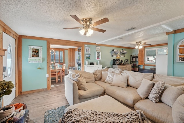 living room with baseboards, visible vents, ceiling fan, a textured ceiling, and light wood-type flooring