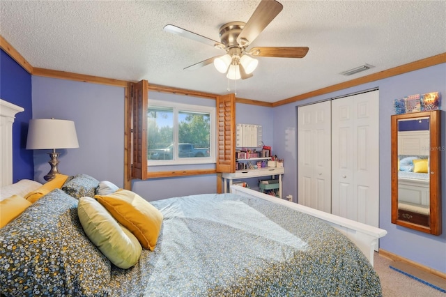 carpeted bedroom with visible vents, ornamental molding, a textured ceiling, a closet, and ceiling fan