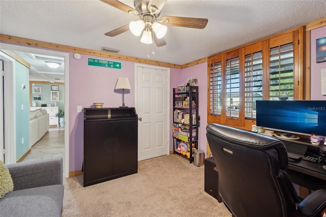 office area with visible vents, baseboards, light carpet, a textured ceiling, and a ceiling fan