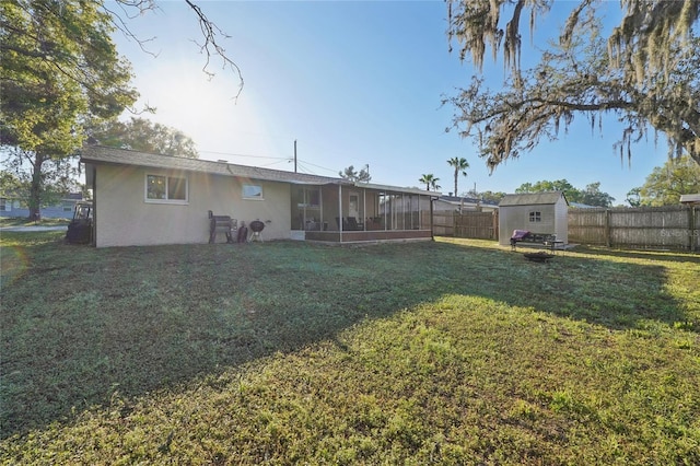 back of property featuring a sunroom, a lawn, a fenced backyard, and stucco siding