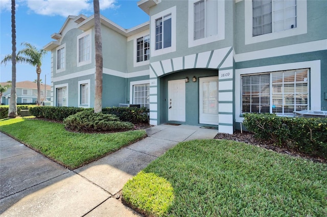 doorway to property with a lawn and stucco siding