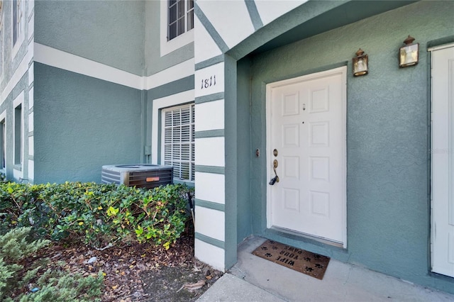 entrance to property with central air condition unit and stucco siding