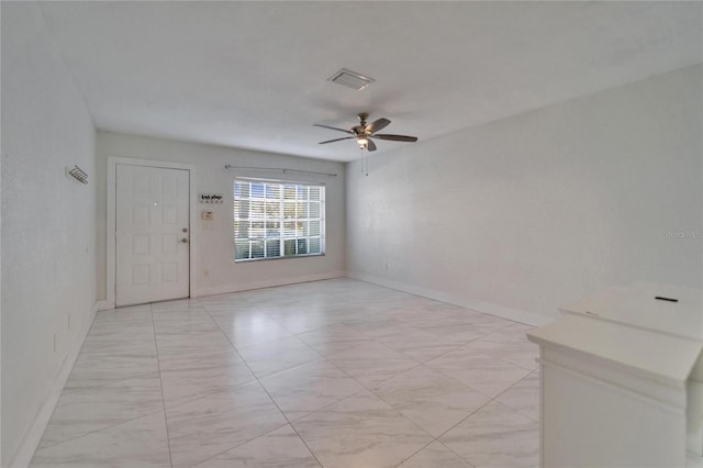 empty room with visible vents, a ceiling fan, and baseboards