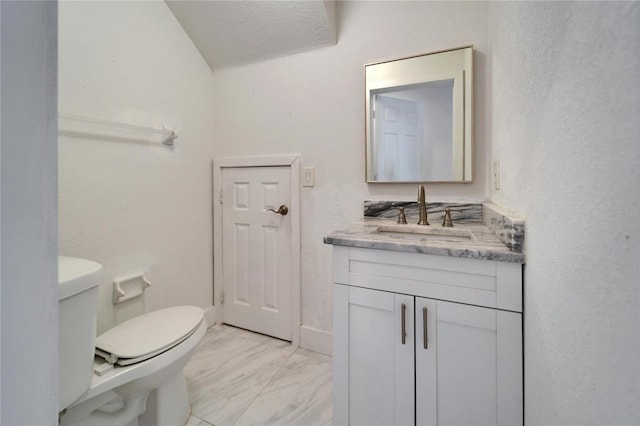 half bath featuring vanity, toilet, baseboards, and marble finish floor