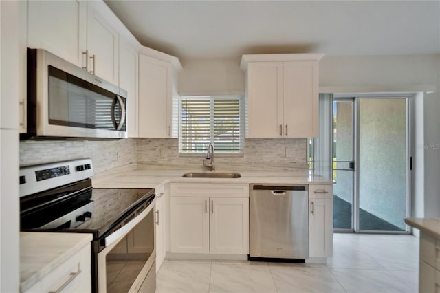 kitchen with backsplash, white cabinetry, stainless steel appliances, and a sink