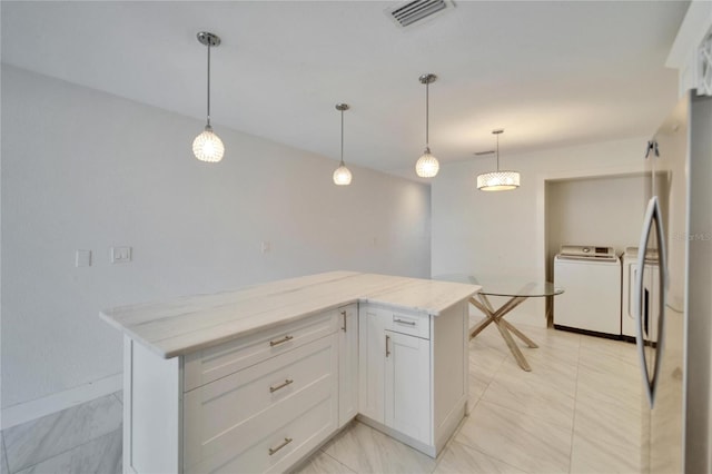 kitchen with washing machine and clothes dryer, visible vents, a center island, light stone countertops, and white cabinets