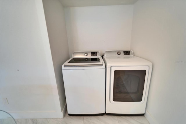 clothes washing area featuring laundry area, baseboards, and washing machine and clothes dryer