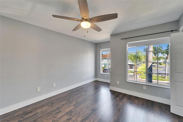 spare room featuring baseboards, dark wood-type flooring, and ceiling fan