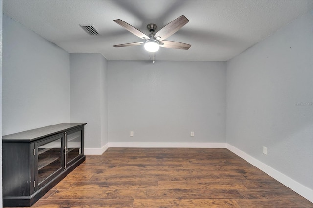 unfurnished room with baseboards, visible vents, dark wood-style flooring, ceiling fan, and a textured ceiling