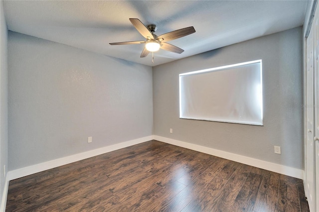 spare room featuring a ceiling fan, dark wood-type flooring, and baseboards