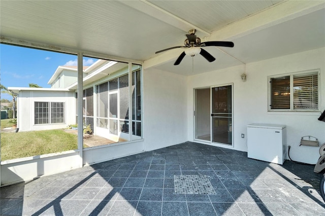 unfurnished sunroom with beamed ceiling, plenty of natural light, and ceiling fan