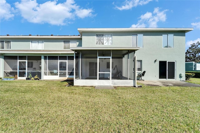 rear view of property with stucco siding, a lawn, and a sunroom