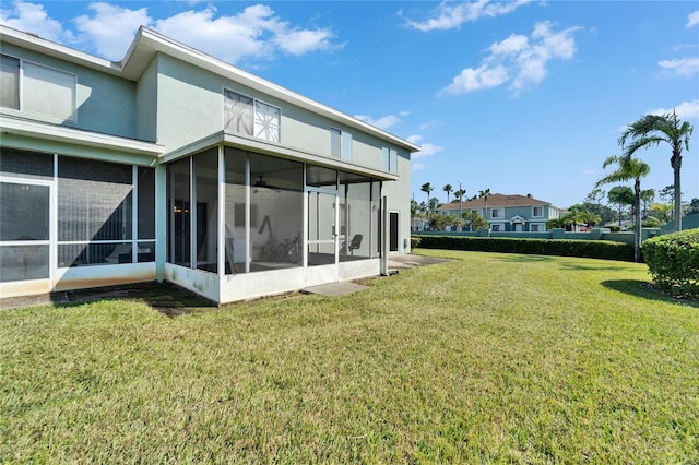 back of property with a yard, a sunroom, and stucco siding