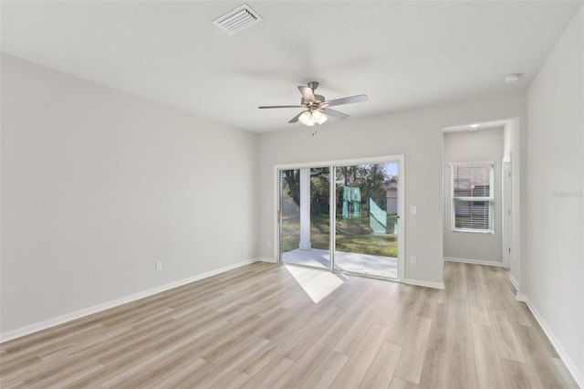 empty room featuring ceiling fan, light wood-style floors, visible vents, and baseboards