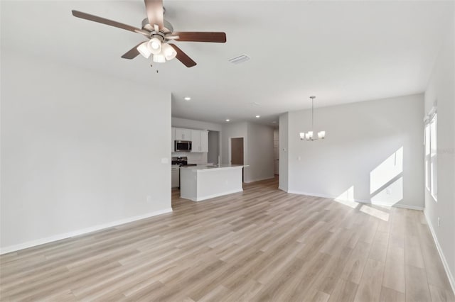 unfurnished living room with recessed lighting, baseboards, ceiling fan with notable chandelier, and light wood finished floors