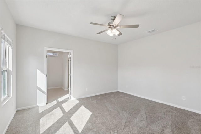 carpeted empty room with visible vents, ceiling fan, and baseboards